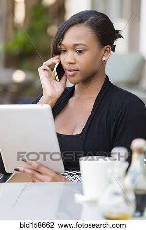 Stock Image - Mixed race businesswoman working at outdoor cafe. Fotosearch
