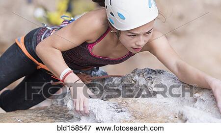 Stock Photo - Mixed race girl climbing rock wall. Fotosearch