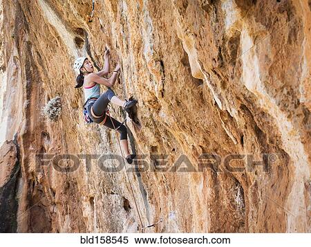 Stock Photography - Mixed race girl climbing rock wall. Fotosearch
