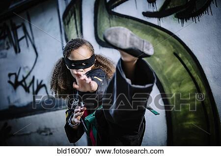 Stock Photo - Mixed race girl kicking in martial arts uniform and mask. Fotosearch