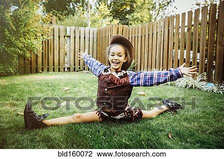 Stock Image - Mixed race girl wearing cowboy costume in backyard. Fotosearch
