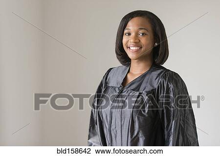 Stock Image - Mixed race graduate smiling in graduation robe. Fotosearch