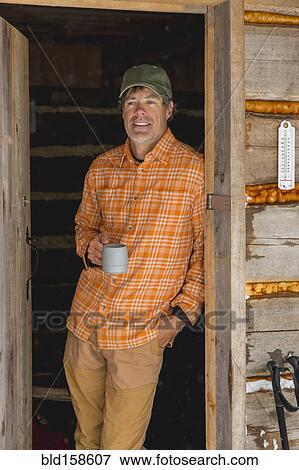 Mixed race man drinking coffee in log cabin doorway View Large Photo Image Stock Photo - Mixed race man drinking coffee in log cabin doorway. Fotosearch