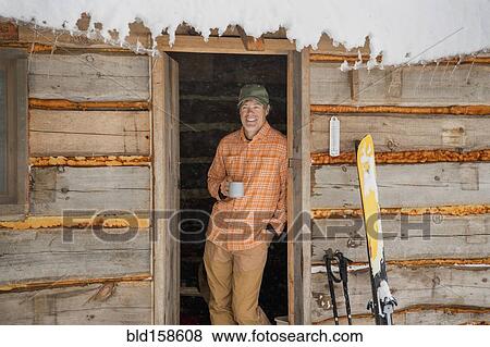 Mixed race man drinking coffee in log cabin doorway in snow View Large Photo Image Stock Photo - Mixed race man drinking coffee in log cabin doorway in snow. Fotosearch