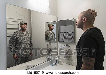 Stock Photo - Mixed race man seeing soldier in mirror. Fotosearch