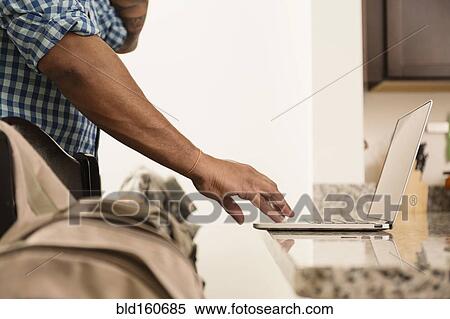 Stock Photography - Mixed race man using laptop on counter. Fotosearch