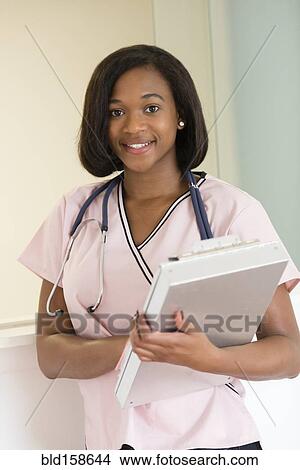 Picture - Mixed race nurse holding medical chart. Fotosearch