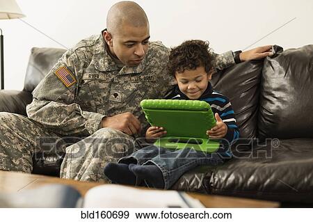 Mixed race soldier father and son using digital tablet on sofa View Large Photo Image Stock Photo - Mixed race soldier father and son using digital tablet on sofa. Fotosearch