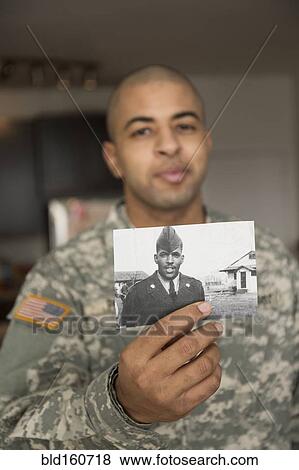 Stock Photo - Mixed race soldier holding photograph of father. Fotosearch