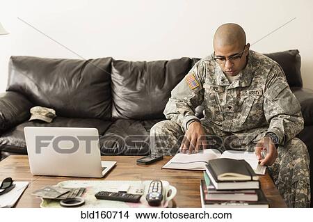 Picture - Mixed race soldier studying on sofa. Fotosearch