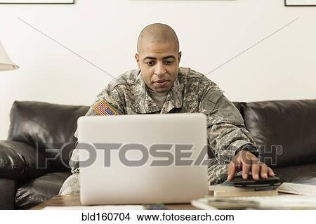 Mixed race soldier using laptop on living room sofa View Large Photo Image Picture - Mixed race soldier using laptop on living room sofa. Fotosearch