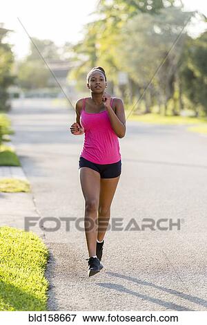 Stock Photo - Mixed race woman jogging on suburban sidewalk. Fotosearch