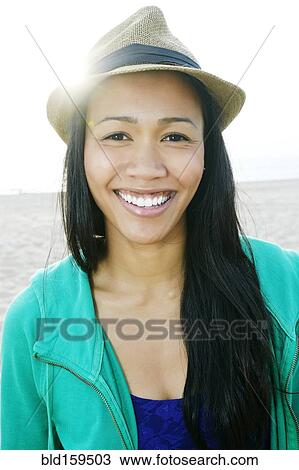 Stock Image - Mixed race woman smiling on beach. Fotosearch