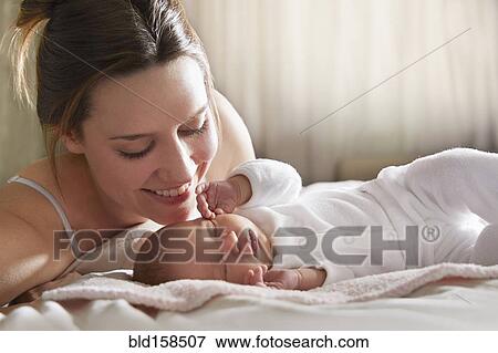Stock Photo - Mother admiring newborn baby on bed. Fotosearch
