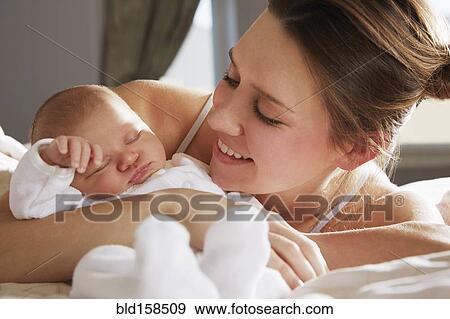 Mother hugging newborn baby on bed View Large Photo Image Stock Photo - Mother hugging newborn baby on bed. Fotosearch