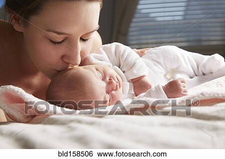 Stock Photograph - Mother kissing newborn baby on blanket. Fotosearch
