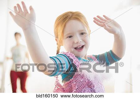 Stock Image - Mother watching Caucasian girl playing dress-up. Fotosearch