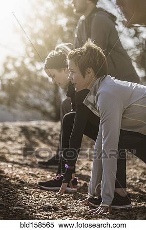 Stock Photography - Runners stretching on dirt ground. Fotosearch