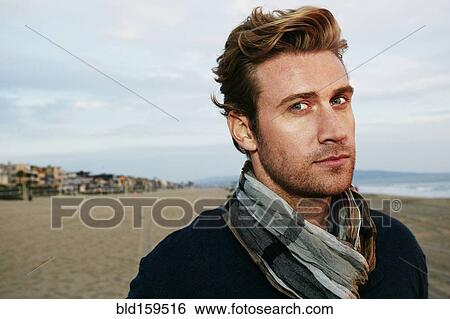 Stock Photograph - Serious Caucasian man standing on beach. Fotosearch
