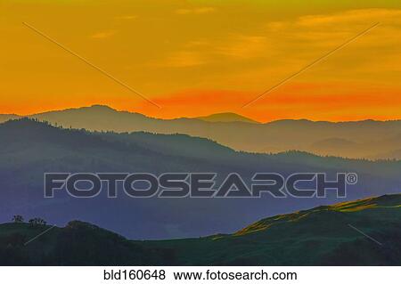 Stock Photo - Silhouette of remote hills under sunset sky. Fotosearch