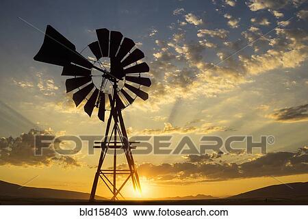 Stock Image - Silhouette of windmill under dramatic sunset sky. Fotosearch