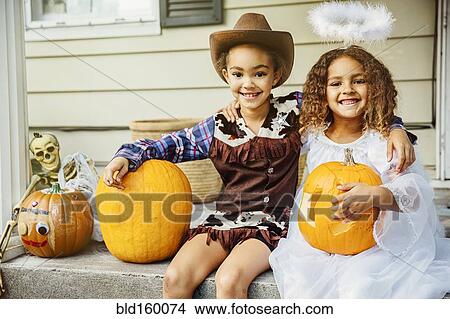 Sisters wearing Halloween costumes with jack-o-lanterns on porch View Large Photo Image Picture - Sisters wearing Halloween costumes with jack-o-lanterns on porch. Fotosearch