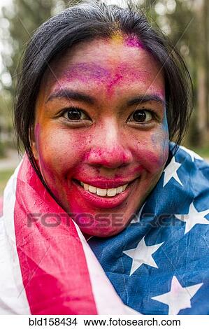 Picture - Smiling Asian woman covered in pigment powder wearing American flag. Fotosearch