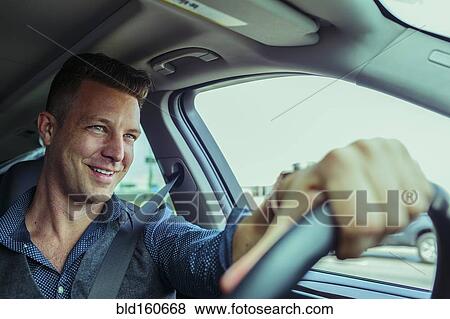 Stock Photo - Smiling Caucasian man driving car. Fotosearch