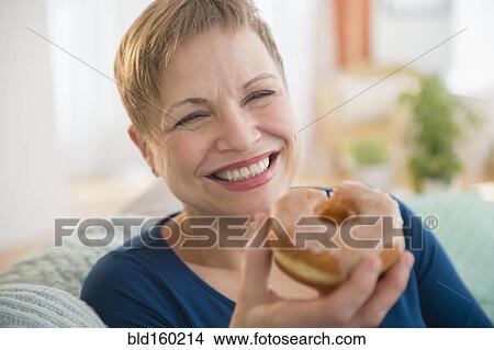 Smiling Caucasian woman eating donut View Large Photo Image Picture - Smiling Caucasian woman eating donut. Fotosearch