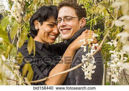 Stock Image - Smiling couple hugging in foliage. Fotosearch