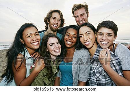 Stock Photography - Smiling friends standing on beach. Fotosearch