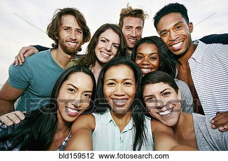 Stock Image - Smiling friends taking selfie outdoors. Fotosearch