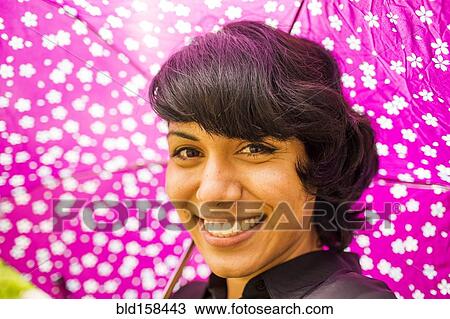 Smiling Hispanic woman holding pink umbrella View Large Photo Image Stock Image - Smiling Hispanic woman holding pink umbrella. Fotosearch