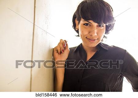 Smiling Hispanic woman leaning on wall View Large Photo Image Stock Photograph - Smiling Hispanic woman leaning on wall. Fotosearch