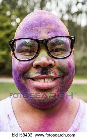 Stock Image - Smiling man covered in pigment powder. Fotosearch