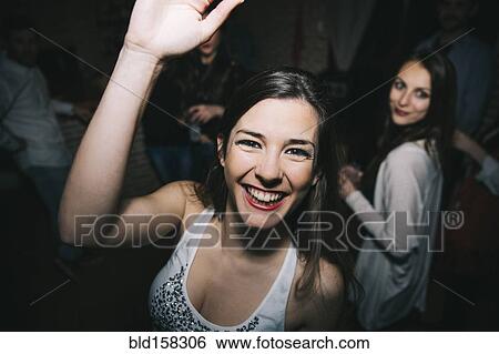 Stock Photograph - Smiling woman waving in nightclub. Fotosearch