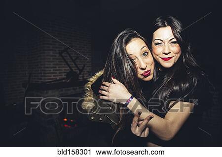 Stock Image - Smiling women hugging at party. Fotosearch