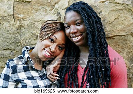 Smiling women hugging near rock wall View Large Photo Image Stock Photograph - Smiling women hugging near rock wall. Fotosearch