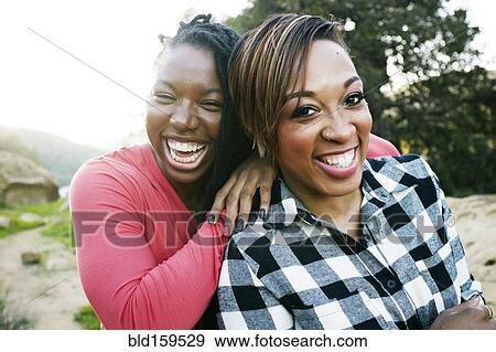 Stock Photo - Smiling women hugging outdoors. Fotosearch