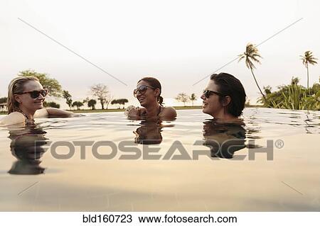 Smiling women relaxing in infinity pool View Large Photo Image Stock Image - Smiling women relaxing in infinity pool. Fotosearch