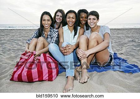 Smiling women sitting on blanket on beach View Large Photo Image Stock Image - Smiling women sitting on blanket on beach. Fotosearch