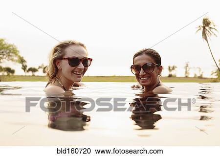 Smiling women swimming in infinity pool View Large Photo Image Stock Image - Smiling women swimming in infinity pool. Fotosearch