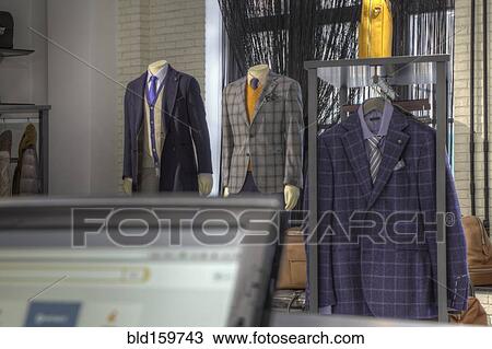 Stock Image - Suits and shoes near cash register in clothing store. Fotosearch