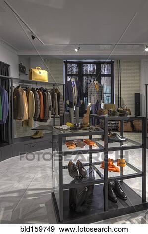 Stock Photo - Suits and shoes on racks in clothing store for men. Fotosearch