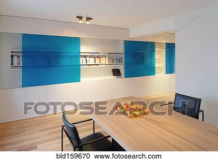Stock Image - Table and chairs near wall fixtures in modern dining room. Fotosearch