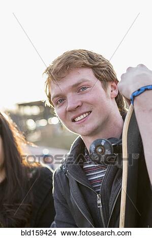 Picture - Teenage boy holding skateboard outdoors. Fotosearch