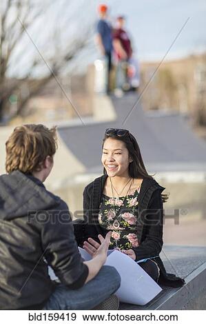 Stock Photo - Teenage couple talking at skateboard park. Fotosearch