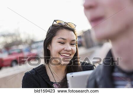 Stock Image - Teenage girl using digital tablet outdoors. Fotosearch