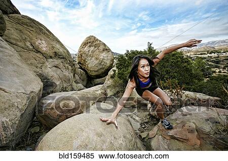 Stock Photography - Vietnamese woman climbing on rocky hillside. Fotosearch