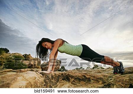 Vietnamese woman doing push-ups on rocky hilltop View Large Photo Image Stock Image - Vietnamese woman doing push-ups on rocky hilltop. Fotosearch